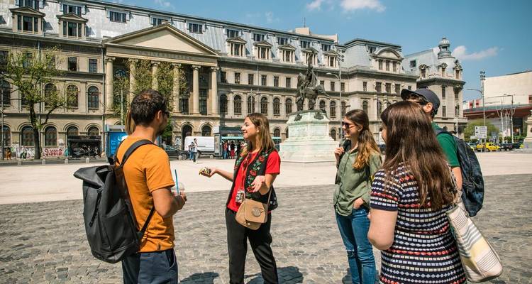 Guide talks to travelers in Bucharest’s grand plaza flanked by neoclassical buildings.