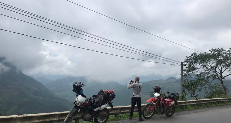 Motociclista tomando una foto de una vista montañosa escénica.