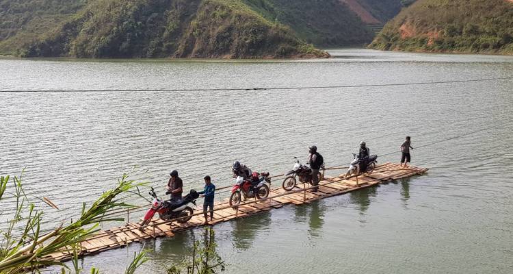 Motorrijders op een bamboe vlot die een rivier oversteken.