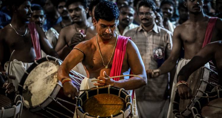 Een groep mannen die traditionele trommels bespelen met één man op de voorgrond