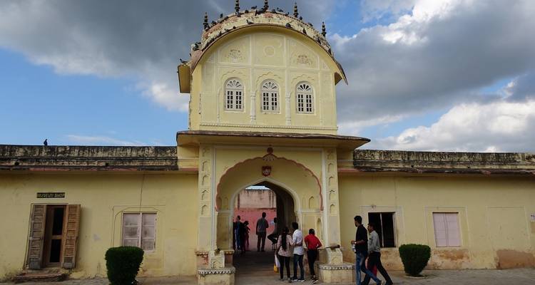 Menschen in der Nähe des Eingangstors eines alten Gebäudes in Jaipur, Indien.