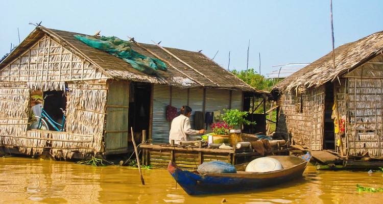 Wooden houses on stilts on a river with a boat.