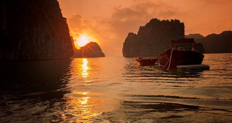 Sonnenuntergang über Booten auf dem Wasser mit Kalksteinfelsen