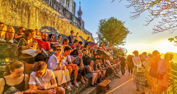 Menigte mensen die op trappen zitten en genieten van de zonsondergang.