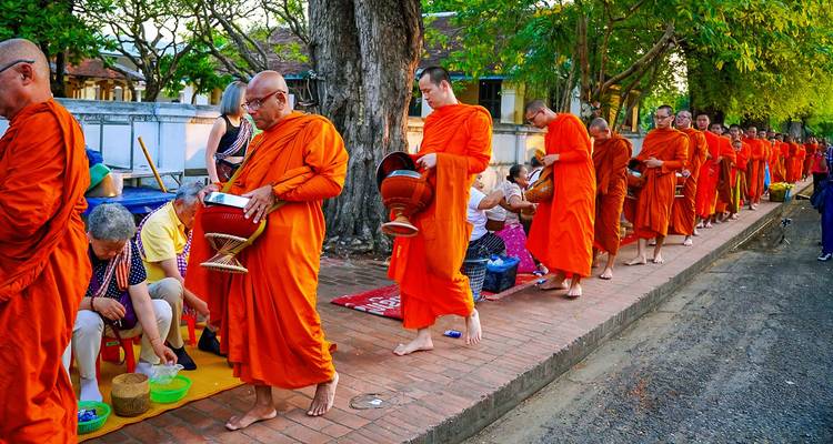 Monniken in oranje gewaden die lopen tijdens een traditionele processieceremonie.
