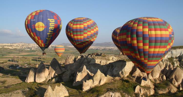Heteluchtballons die over rotsformaties vliegen.