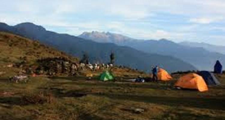 Campingplatz mit Menschen unter Zelten in einer Berglandschaft.