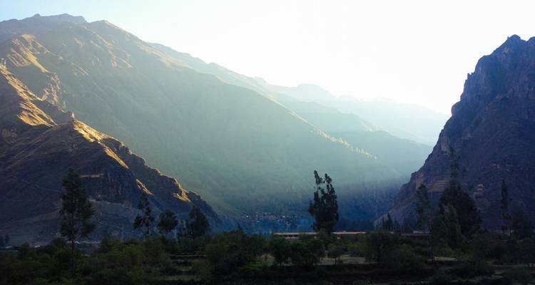 Bergdal met bomen en zonlicht dat delen van het landschap verlicht
