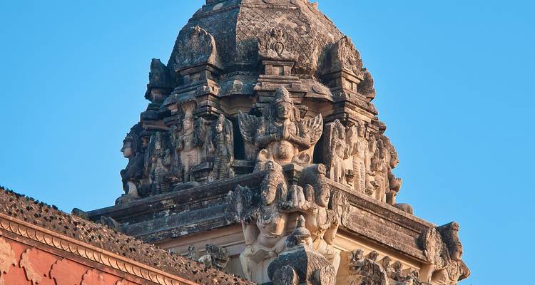 Tempelkuppel mit aufwendigen Schnitzereien vor blauem Himmel.