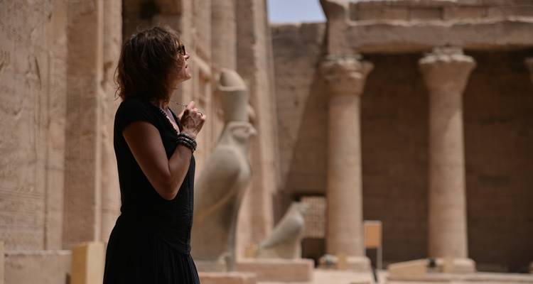 Persoon die voor oude ruïnes en zuilen staat.