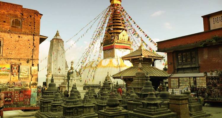 Buddhistische Stupa geschmückt mit bunten Flaggen in historischer Umgebung.