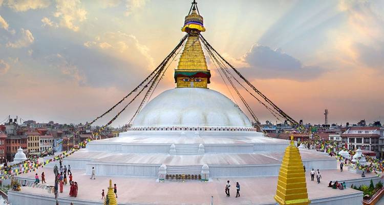 Eine große Stupa mit Augen unter einem dramatischen Himmel in einer Stadtlandschaft.