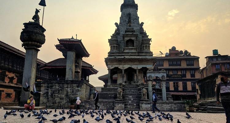 Ein alter Tempel mit Tauben im Vordergrund, unter einem sanften Himmel.