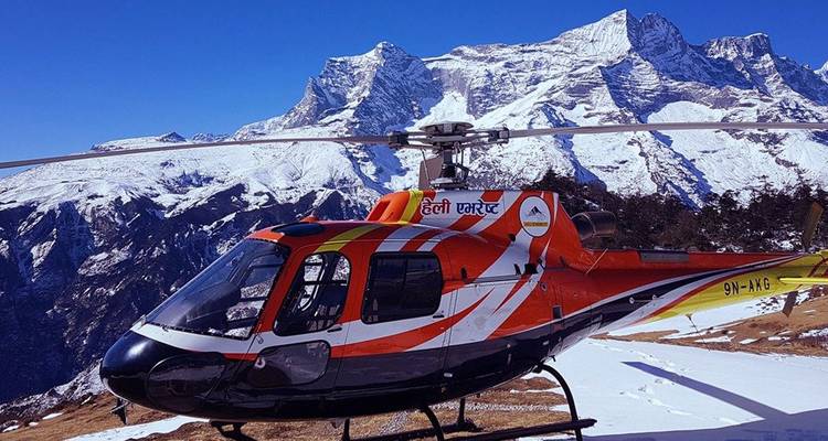 Helikopter geparkeerd op besneeuwde terrain met bergen op de achtergrond.