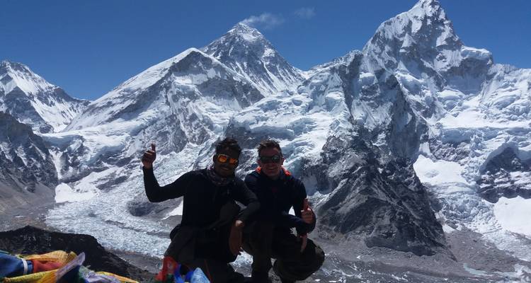 Twee klimmers die vieren op een schilderachtig uitkijkpunt met bergen op de achtergrond.
