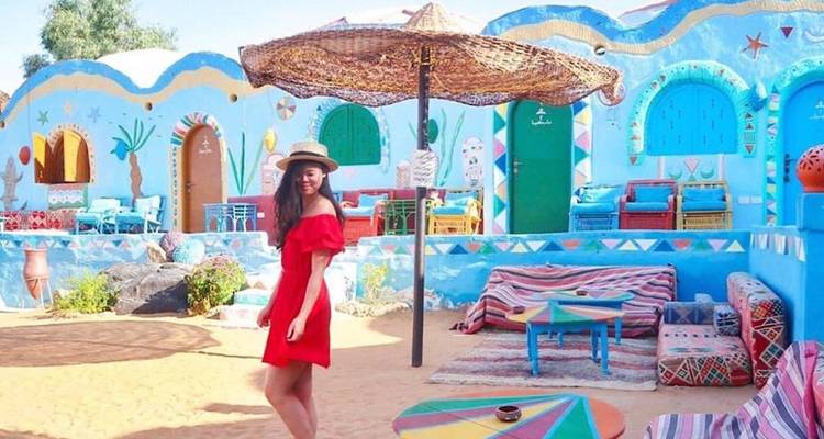 Kleurrijk Nubisch dorp met een persoon in een rode jurk die poseert.