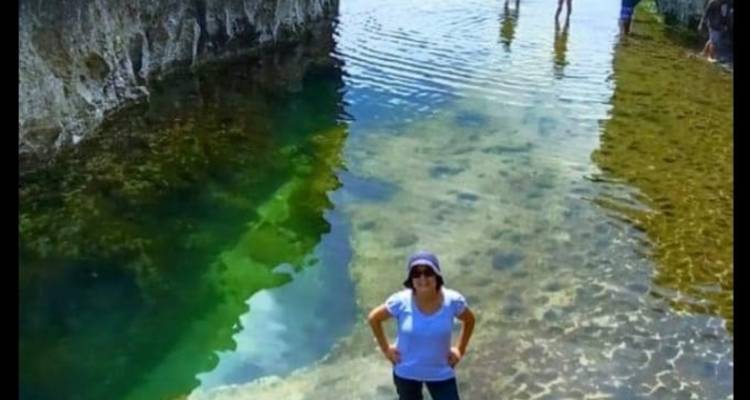 Person, die in seichtem Wasser steht, umgeben von Klippen.