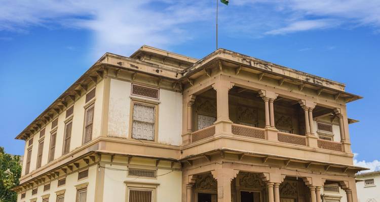 Historisch gebouw met een vlag erop onder een heldere hemel.