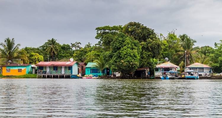 Colorful houses along the water in a tropical setting with lush greenery.
