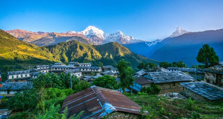 Village with stone houses in front of a mountain backdrop.