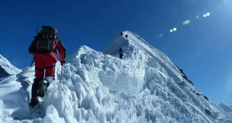 Bergsteiger auf einem verschneiten Bergkamm unter klarem Himmel.