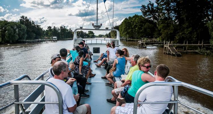 People enjoying a boat ride on a river lined with trees.