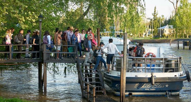 Group of people embarking on a boat at a wooden dock.