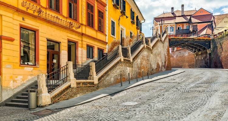 Colorful historic street and terraced staircase leading to the iconic Bridge of Lies in Sibiu.