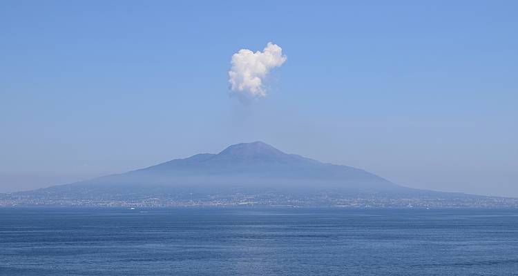 Fernblick auf einen Berg mit einer Wolke darüber, gesehen über einem Gewässer.
