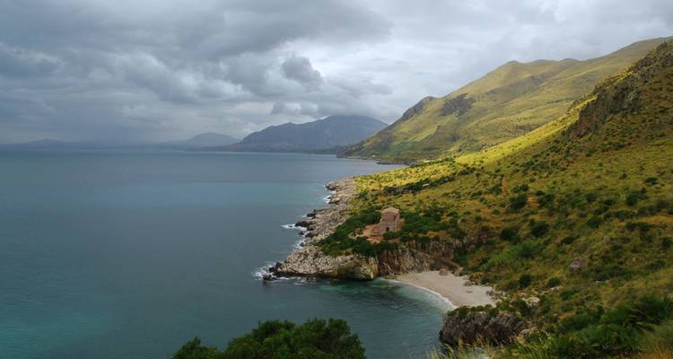 Küstenlandschaft mit Bergen und einem felsigen Strand.