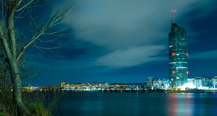 Vista nocturna de un rascacielos moderno junto al agua.