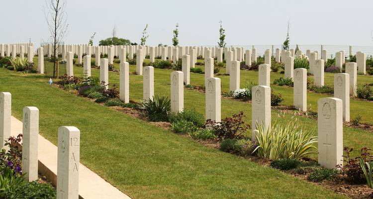Ein Friedhof mit Reihen ordentlicher Grabsteine unter einem klaren Himmel.