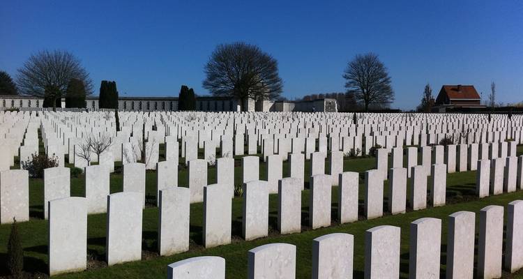 Militärfriedhof mit Reihen von Grabsteinen vor einem blauen Himmel.