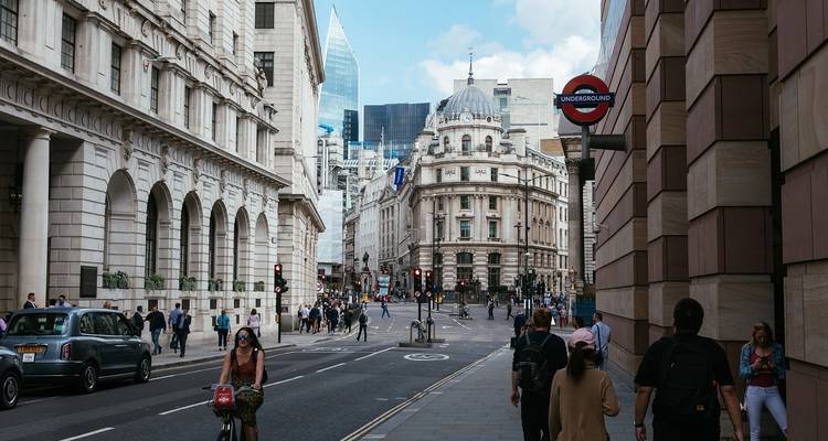 Drukke straat in Londen met voetgangers en klassieke gebouwen.