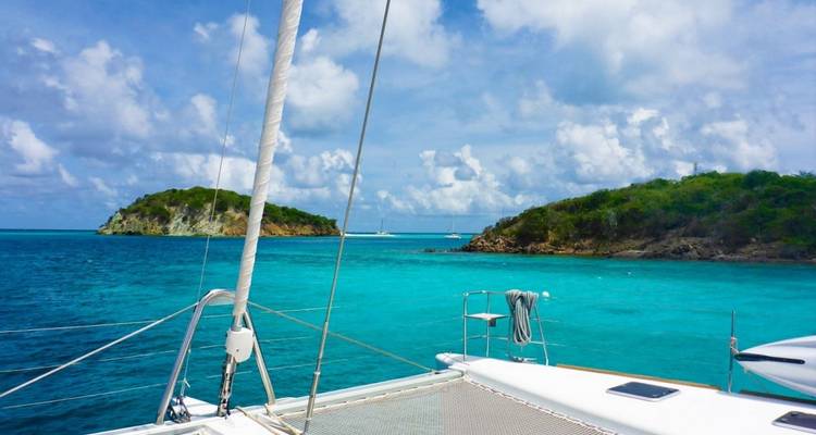 View from the deck of a sailboat sailing through turquoise waters.