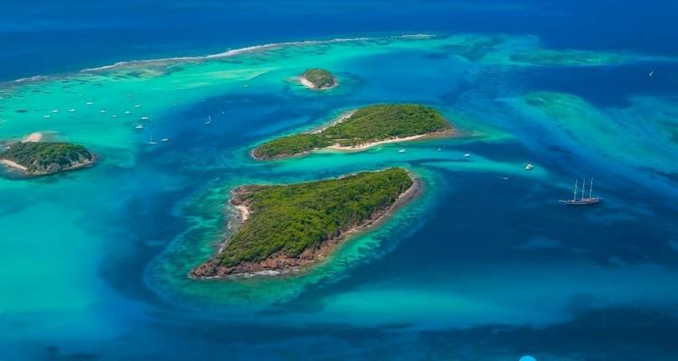 Arial view of small green islands surrounded by clear blue water.