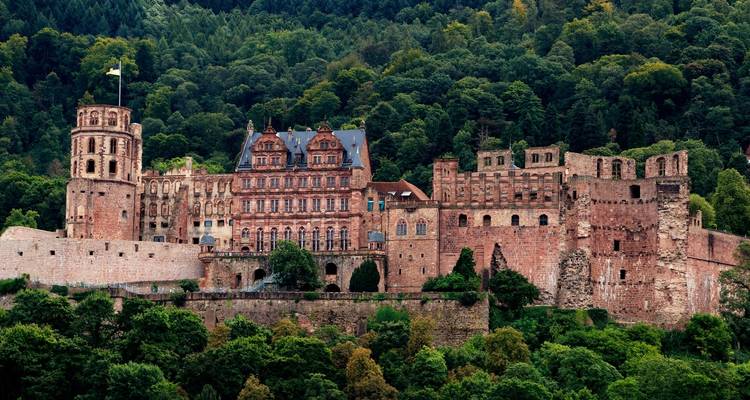 Castillo majestuoso enclavado en colinas verdosas.