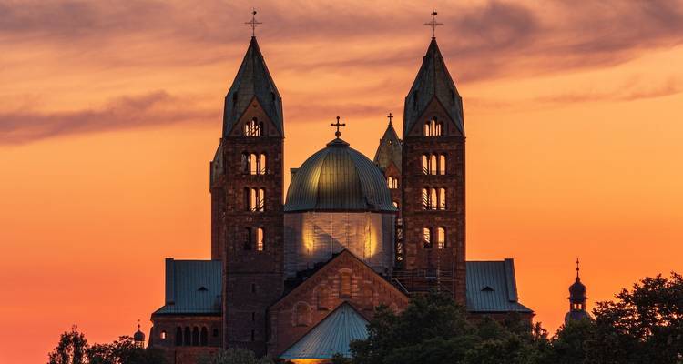 Iglesia de dos torres recortada contra un cielo naranja.