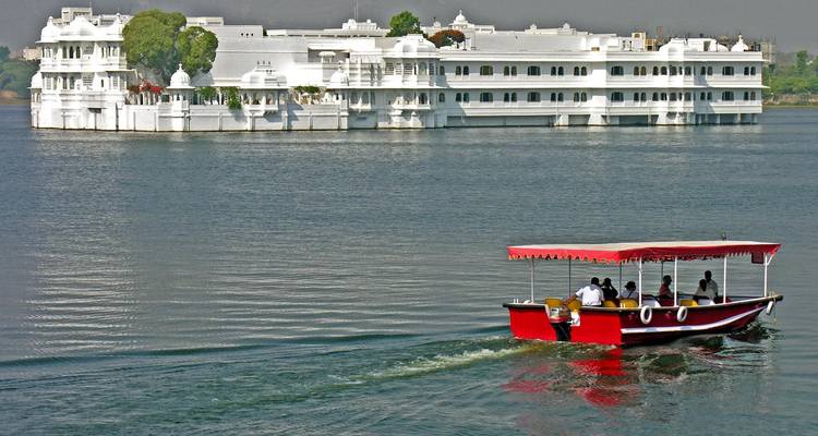 Boot auf einem See mit einem weißen Palast im Hintergrund.
