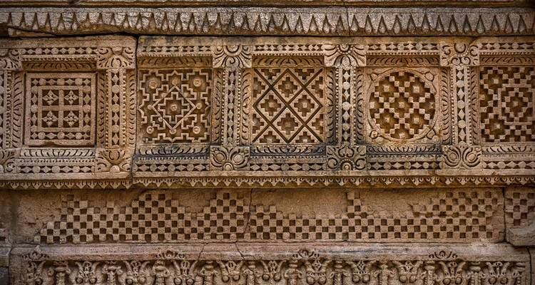 Sierlijke stenen muur met geometrische patronen.