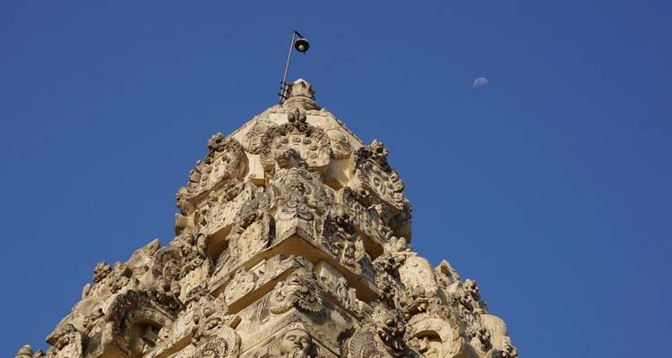 Eine Tempelstruktur mit kunstvollen Schnitzereien und einer Flagge oben darauf.