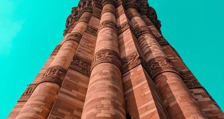 Een hoge, ingewikkelde stenen toren met gravures tegen een heldere blauwe lucht.