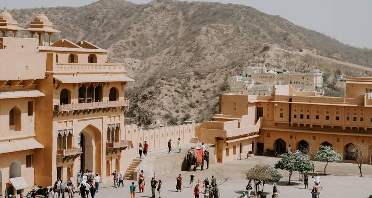 Zicht op een fort in een woestijnlandschap met bezoekers en een olifant.