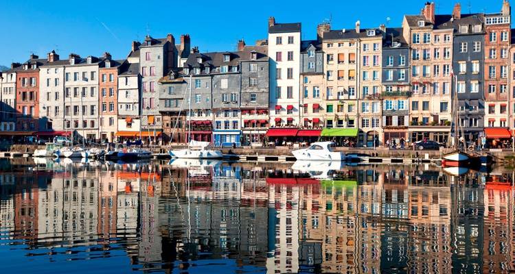 Bâtiments colorés au bord de l'eau avec des yachts et des reflets dans l'eau.