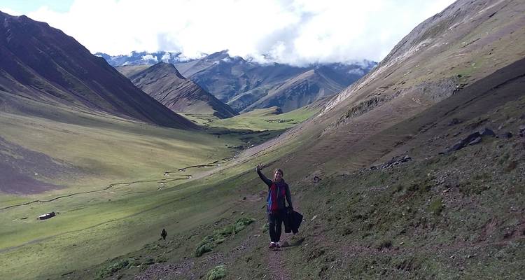 Wandelaar die zwaait in een weelderige bergvallei.