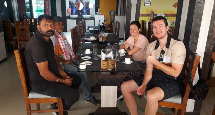 Un petit groupe assis autour d'une table de restaurant avec des tasses et des assiettes pendant un repas.