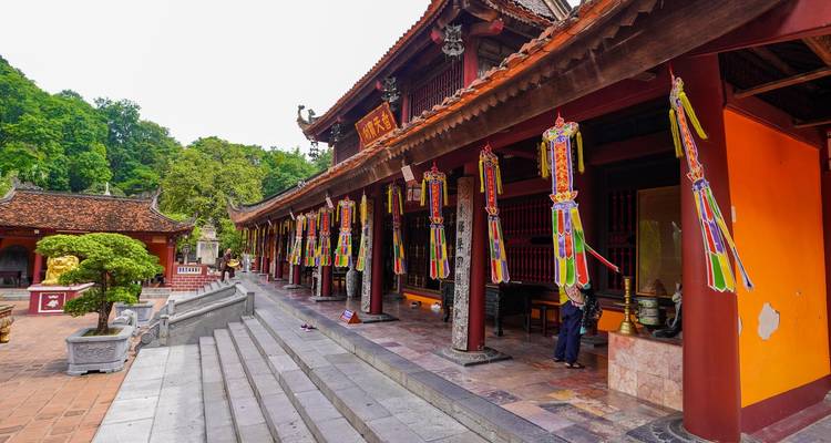 Brillantes banderas de oración coloridas cuelgan de los aleros de madera de un corredor de templo ornamentado.