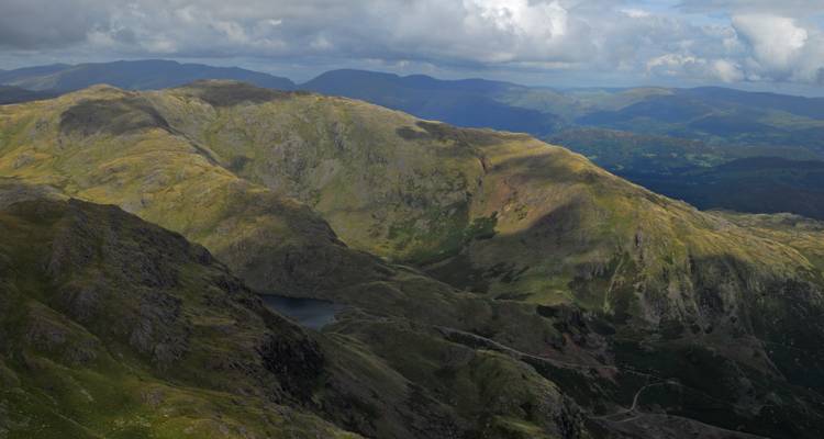 Malerische Aussicht auf eine weitläufige Gebirgskette unter einem bewölkten Himmel.