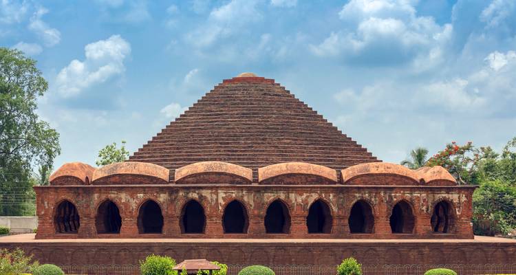 Frontal symmetrical shot of Rasmancha terracotta monument beneath a vibrant sky.