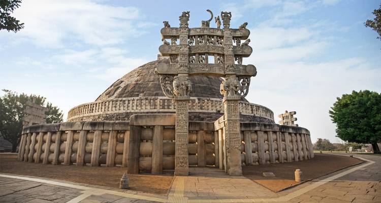 Stupa met gedetailleerde gravures, omringd door groen.